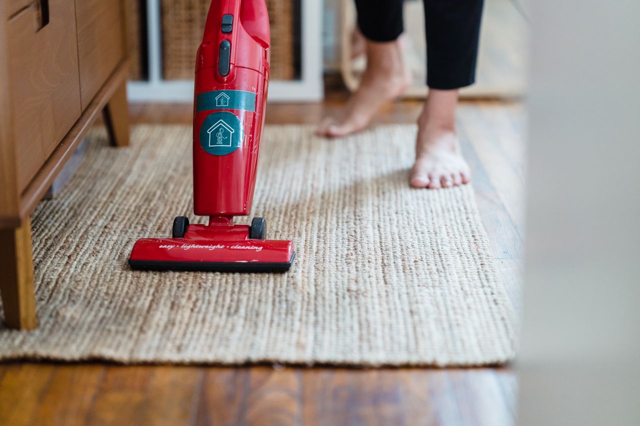 why-choose-us A red vacuum cleaner on a carpet in a stylish home setting with barefoot user.